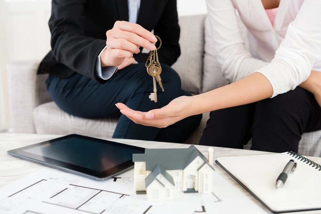 A man and woman are holding keys to their new home.