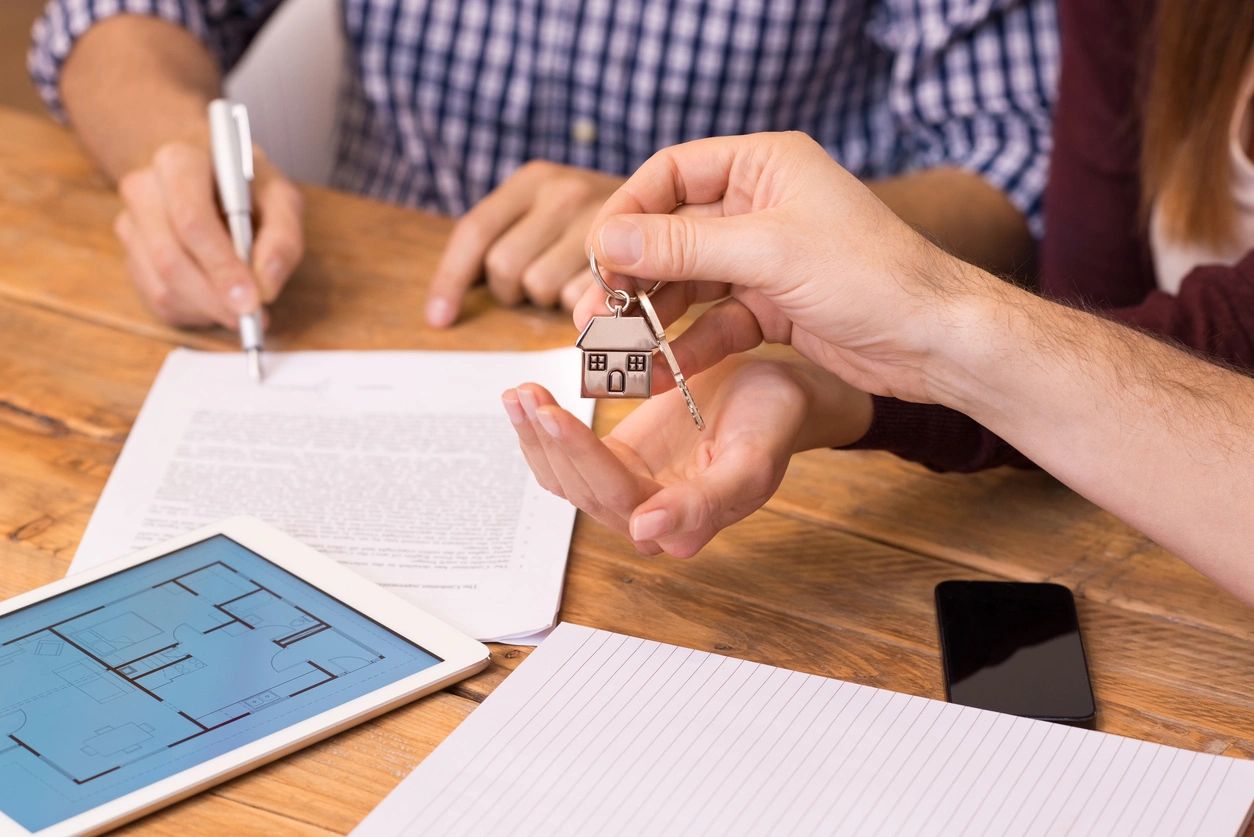 Two people are holding keys to a house.